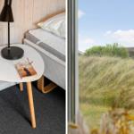 Schlafzimmer mit Bett, Tisch und Lampe. Aussicht auf Gras und Himmel.