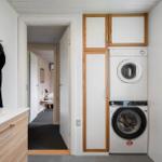 Wäscherei mit Waschmaschine und Trockner, integriert in Holzschrankwand. Blick in Schlafzimmer.