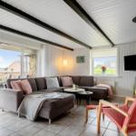 Wohnzimmer mit Sofa, roter Sitzgelegenheit und Kamin. Große Glasfront zum Balkon.