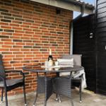 Terrasse mit Tisch und zwei Stühlen vor roter Ziegelwand.