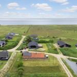 Aerial view of holiday homes on green meadows near sea.