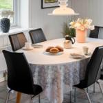 Runde Tafel mit Tischdecke, Stühle, Kaffeetasse und Brötchen.
