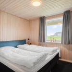Schlafzimmer mit Holzwand und Fensterblick auf Grünfläche.