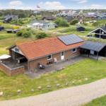 Ein Haus mit rotem Dach und Solaranlage auf grünem Grundstück mit Terrasse und Garten.