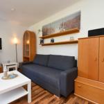 Wohnzimmer mit Sofa, TV, Schränken und Holzboden.
