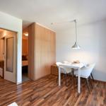Essbereich mit weißem Tisch und Stühlen. Holzboden und Fenster mit Vorhängen.