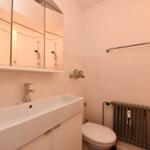 Badezimmer mit Waschbecken, Spiegel, Toilette und Heizkörper.