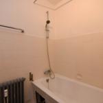 Bad mit Badewanne, Duschbrause und Heizkörper an der Wand.