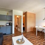 Wohnung mit Küche, Essbereich und Schlafzimmer. Holzboden und moderne Möbel.