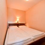Ein Schlafzimmer mit Doppelbett, weißen Bettwäsche und einer Wandlampe.