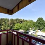 Balkon mit Blick auf Bäume und Wohnmobile.