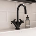 Schwarzer Wasserhahn auf weißem Waschbecken mit Seifenspender.