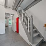 Haus mit Treppe, rotem Kühlschrank und Fensterblick ins Grüne.