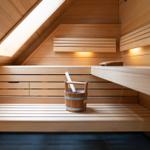Sauna mit Holzbank, Holzwanne und Dachfenster. Fliesenboden und Holzwände.