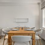 Esszimmer mit Holztisch, grauen Stühlen und Fenster mit Lampe.