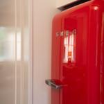 Roter Kühlschrank mit Chromgriff und Markenlogo an der Wand