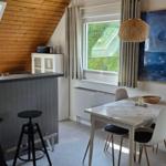 Essbereich mit Tisch, Stühlen und Fenstern. Bar mit Hocker und Fernseher. Holzwand im Dachbereich.
