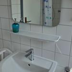 Badezimmer mit Waschbecken, Spiegel und Dusche mit Vorhang.