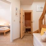 Schlafzimmer mit Bett, Sauna und Holztreppe mit Teddybärenbank.