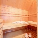 Sauna mit Holzbank, Handtuch und Blume. Holzfußboden und Schuhe.