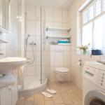 Badezimmer mit Dusche, Waschbecken, Toilette und Waschmaschine.