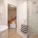 Badezimmer mit Dusche, Waschbecken und Blick in die Treppe.
