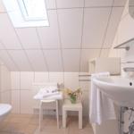 Badezimmer mit Dachfenster, Waschbecken, Toilette und Handtuchständer.