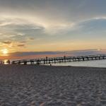 Sonnenuntergang am Strand mit Steg und Strandkorb.