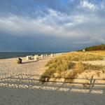 Strand mit Sanddünensystem und Strandkörben unter bewölktem Himmel
