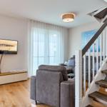 Wohnzimmer mit Sofa, Fernseher und Treppe.