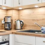 Küche mit Holzwand, Spüle, Kaffeemaschine und Wasserkocher.