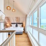 Schlafzimmer mit Blick aufs Meer, großes Fenster, Bett und TV.