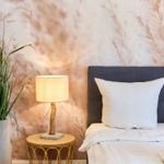 Schlafzimmer mit Bett, Nachttisch und Pflanzen an der Wand mit Muster.