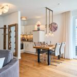 Wohn- und Essbereich mit Holzboden, Esstisch, Küchenzeile und Terrasse.