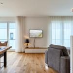 Wohn- und Essbereich mit Holzboden, TV und Essplatz.