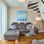 Wohnzimmer mit grauem Sofa, Stehlampe und Bild an der Wand