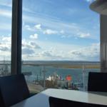 Ein Essbereich mit Blick auf Hafen und Meer unter blauem Himmel mit Wolken.