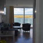Wohnung mit Blick auf Wasser und Strand. Möbel und Küchenzeile sichtbar.