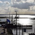 Hafen mit Steg, Flaggen und Blick auf Wasser und Horizont.