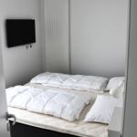 Schlafzimmer mit Doppelbett, Fernseher und Heizung.