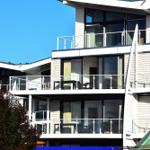 Modernes Mehrfamilienhaus mit Balkonen und großen Fenstern unter blauem Himmel.