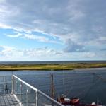 Terrasse mit Blick auf Hafen und Meer unter bewölktem Himmel.