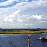 Hafen mit Booten und Blick auf zwei Kreuzfahrtschiffe im Meer.
