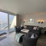 Wohnzimmer mit Sofa, Sesseln und Blick auf den Hafen.
