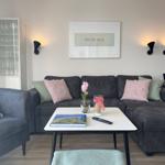 Ein Wohnzimmer mit grauem Sofa, Tisch und Wandbild.