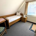 Ein Schlafzimmer mit Einzelbett, Schreibtisch und Fenster mit Vorhängen.