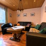 Wohnzimmer mit zwei Sofas, einem Sessel und einem Holztisch. Holzfußboden und Holzdecke.