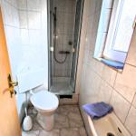 Badezimmer mit Dusche, Toilette und Waschbecken. Fenster mit Handtuch.