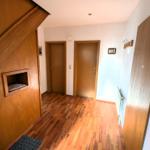 Flur mit Holzboden, zwei Türen und Holzwand mit eingelassener Nische.