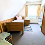 Schlafzimmer mit Bett, Stuhl, Schrank und Fenster mit Vorhängen.